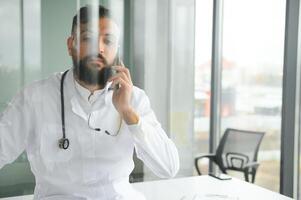 Porträt von ein jung arabisch Arzt im das Klinik. Gesundheitswesen Konzept foto