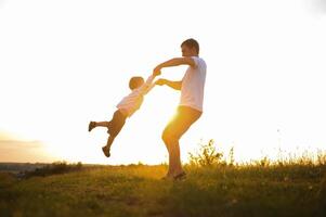 Vaters Tag. glücklich Familie Vater und Kleinkind Sohn spielen und Lachen auf Natur beim Sonnenuntergang foto