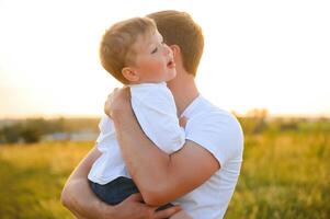 Vaters Tag. glücklich Familie Vater und Kleinkind Sohn spielen und Lachen auf Natur beim Sonnenuntergang foto