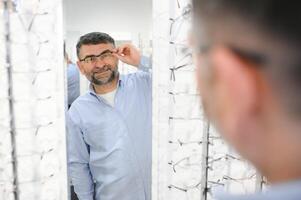 Brille überprüfen, Senior Vision und Alten Mann beim ein Beratung Optometrie Klinik zum Wohlbefinden. Glücklich, Lächeln und alt Gesicht mit Linse, Rahmen und Brillen Wahl im ein Geschäft zum Hilfe bekommen ein Verschreibung. foto