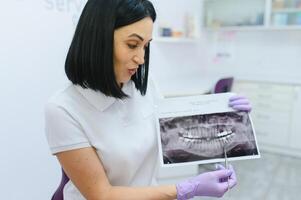 Zahnarzt Show durch ihr Finger auf das Milch Zahn auf das Röntgen Zähne Bild schließen hoch. foto