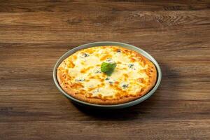 quattro Formaggi Pizza serviert im ein Gericht oben Aussicht auf dunkel hölzern Hintergrund foto