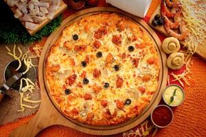 Meeresfrüchte Pizza mit Tomate Soße und Mayo isoliert auf hölzern Tafel oben Aussicht von Italienisch Essen auf hölzern Hintergrund foto
