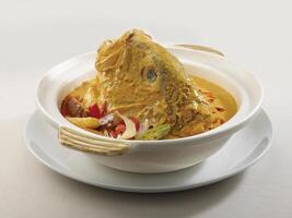 gedünstet Fisch Kopf mit Curry im Tontopf serviert im ein Gericht isoliert auf hölzern Tafel Seite Aussicht dunkel Hintergrund foto