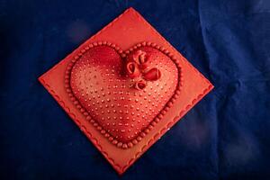 Herz geformt rot Kuchen mit Rose Blumen, Messer und Gabel serviert auf Tafel isoliert auf Serviette oben Aussicht von Cafe gebacken Essen foto