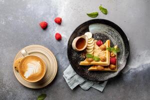 Banoffee Waffel mit Cappuccino, Himbeere und Banane serviert im Gericht isoliert auf Tabelle oben Aussicht von Arabisch Frühstück foto