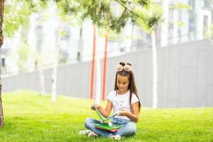 wenig Mädchen lesen ein Buch im das Frühling Park foto