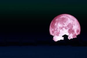 superrosa Mond und Silhouette Damm am dunklen Nachthimmel foto
