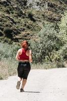 aktives Mädchen, das am Berg läuft, ländlicher Weg foto