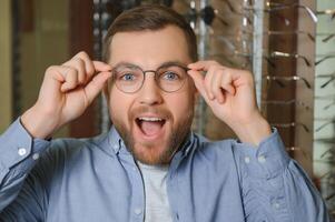 zufrieden Kunde. Über das Schulter Aussicht von glücklich jung männlich Klient tragen Neu Brille. foto