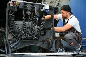 halb LKW unter Wartung. kaukasisch LKW Mechaniker Arbeiten zu Fix das Traktor. foto