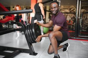 gut aussehend jung afrikanisch amerikanisch Mann Arbeiten aus beim das Fitnessstudio foto