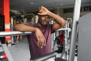 müde afrikanisch amerikanisch Mann müde nach Arbeiten aus im das Fitnessstudio. foto
