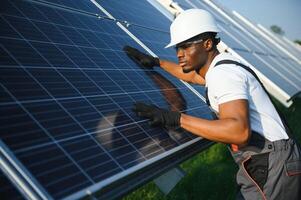 afrikanisch amerikanisch Ingenieur Aufrechterhaltung Solar- Zelle Tafeln. Techniker Arbeiten draussen auf ökologisch Solar- Bauernhof Konstruktion. verlängerbar sauber Energie Technologie Konzept foto