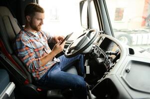 Mann LKW Treiber Sitzung hinter Rad von Auto und halten Digital Tablette im seine Hände foto