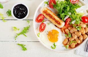 Englisch Frühstück. Keto Frühstück. gebraten Ei, Bohnen, Hähnchen Würstchen und Kaffee Tasse. oben Sicht, eben legen foto