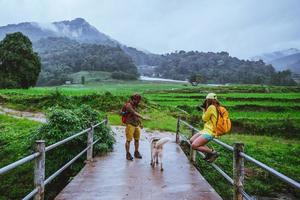 Liebhaber asiatischer Mann asiatische Frauen reisen Natur. wandern ein foto das reisfeld und halt machen eine pause entspannen auf der brücke bei ban mae klang luang in der regenzeit.