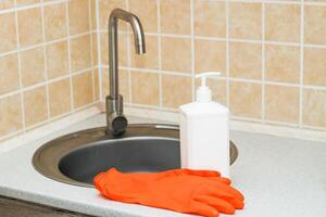 Küche sinken mit Wasserhahn und Handschuhe zum Reinigung und Waschmittel. foto