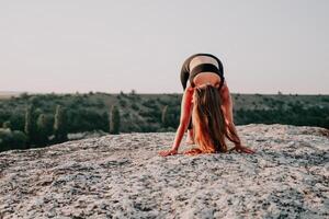 Fitness Frau. Gut suchen Mitte alt Frau mit lange Haar, Fitness Lehrer im Gamaschen und Spitzen tun Dehnen und Pilates auf das Felsen in der Nähe von Wald. weiblich Fitness Yoga Routine Konzept. foto