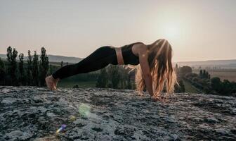 Fitness Frau. Gut suchen Mitte alt Frau mit lange Haar, Fitness Lehrer im Gamaschen und Spitzen tun Dehnen und Pilates auf das Felsen in der Nähe von Wald. weiblich Fitness Yoga Routine Konzept. foto