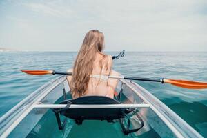 Frau im Kajak zurück Sicht. glücklich jung Frau mit lange Haar schwebend im transparent Kajak auf das Kristall klar Meer. Sommer- Urlaub Ferien und heiter weiblich Menschen entspannend haben Spaß auf das Boot foto