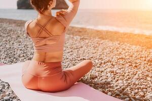 Mitte alt Gut suchen Frau mit schwarz Haar, Fitness Lehrer im Gamaschen und Spitzen tun Dehnen und Pilates auf Yoga Matte in der Nähe von das Meer. weiblich Fitness Yoga Routine Konzept. gesund Lebensstil foto