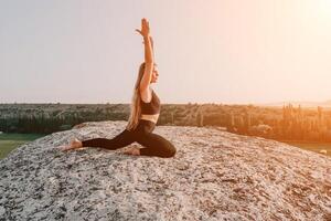 Fitness Frau. glücklich mittleren Alters Fitness Frau tun Dehnen und Pilates auf ein Felsen in der Nähe von Wald beim Sonnenuntergang. weiblich Fitness Yoga Routine. gesund Lebensstil mit Fokus auf Wohlbefinden und Entspannung. foto