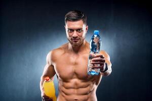 sexy Sportler halten ein Flasche von Wasser und Limonade. wählen zwischen gesund und schädlich trinken. Porträt. Nahansicht foto