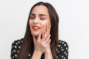 Leiden von Zahnschmerzen. schön jung Frau Leiden von Zahnschmerzen, Stehen gegen Weiß Hintergrund. Dental Pflege Konzept. Menschen Emotionen. foto