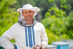 Imker beim Bienenhaus beim das Sommer- Tag. Mann Arbeiten im Bienenhaus. Imkerei. Bienenzucht Konzept. foto