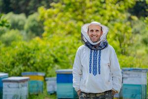 männlich Imker Über Nesselsucht Hintergrund. schützend Hut. verschwommen Hintergrund. Honig und Bienen. foto