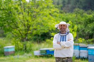 Imker beim Bienenhaus beim das Sommer- Tag. Mann Arbeiten im Bienenhaus. Imkerei. Bienenzucht Konzept. foto