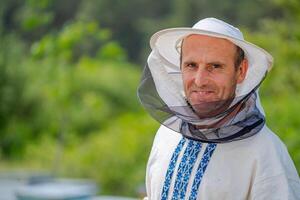 männlich Imker Über Nesselsucht Hintergrund. schützend Hut. verschwommen Hintergrund. Honig und Bienen. foto