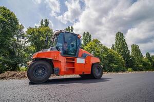 Straße Reparatur, Verdichter liegt Asphalt. schwer Besondere Maschinen. Asphalt Fertiger im Betrieb. Seite Sicht. Nahaufnahme. foto