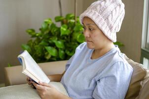 asiatisch Frau mit Krebs sitzt mit ein Buch zu lindern betonen. foto