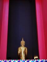 Aussicht von zurück Seite von golden Buddha Statue Skulptur im thailändisch Tempel mit rot Farbe hölzern Rahmen Fenster, thailändisch die Architektur und Kultur foto