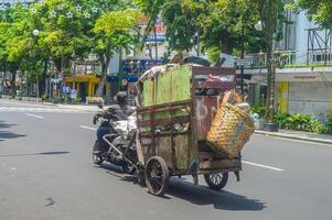 Aasfresser ziehen Müll Karren mit alt Motorräder, Indonesien, 2 März 2024. foto