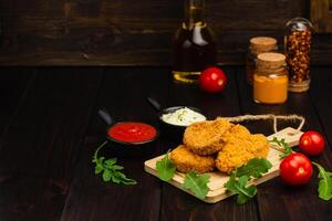 köstlich frisch knusprig Hähnchen Nuggets auf ein dunkel hölzern Hintergrund. ungesund Essen, schnell Essen foto