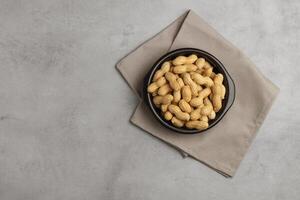 Erdnuss im ein Schüssel auf abspielen Stein Hintergrund oben Aussicht Kopieren Raum. gesund Snack Lebensmittel. foto