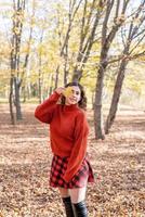 junge glückliche Frau, die im Herbstwald geht foto