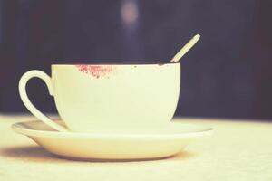 leeren betrunken Tasse auf ein Untertasse mit Lippenstift auf das Rand foto