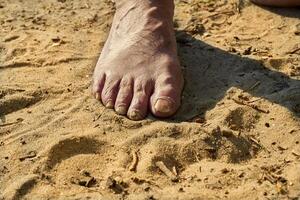 Fuß von ein Alten Mann mit schmerzlich spröde Nägel auf das Sommer- Sand foto