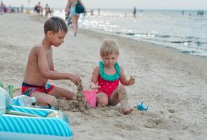 Bruder und Schwester Herstellung Sand Schloss auf das Strand im warm Sommer- Tag.Familie Sommer- Ferien Konzept. hoch Qualität Foto