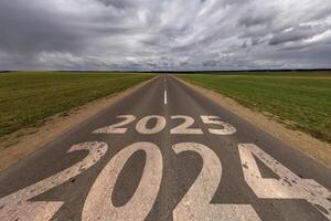 Zeichen 2024, 2025 auf Asphalt Straße Autobahn mit bedeckt Himmel Hintergrund. Konzept von Ziel oder Unsicherheit im Zukunft, Freiheit, Arbeit Start, laufen, Planung, Herausforderung, Ziel, Neu Jahr foto