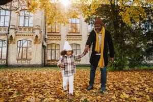 schwarzer Großvater und Enkelin machen Spaß beim gemeinsamen Spielen im Herbstpark foto