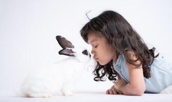ein wenig Mädchen Küsse ihr Geliebte flauschige Kaninchen, das Schönheit von Freundschaft zwischen Menschen und Tiere foto