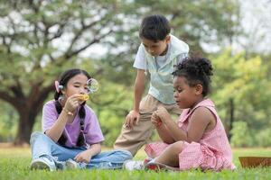 Kinder Sitzung im das Park mit weht Luft Blase, umgeben durch Grün und Natur foto