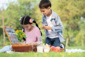 glücklich Familie genießen ein Picknick im das Park, Kinder Sitzung zurück zu zurück und lesen Bücher. foto