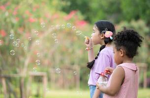 Mädchen im das Park mit weht Luft Blase, umgeben durch Grün und Natur foto