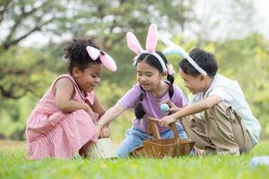 Kinder genießen draussen Aktivitäten im das Park einschließlich ein Lauf zu sammeln schön Ostern Eier. foto